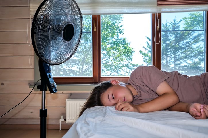 Mujer durmiendo con ventilador: cómo elegir el mejor colchón para calor