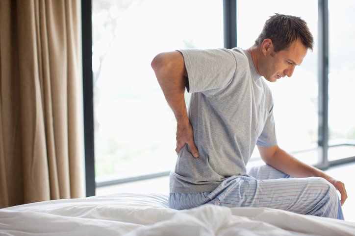 Hombre con dolor lumbar al levantarse: buscar el mejor colchón para dolor de espalda
