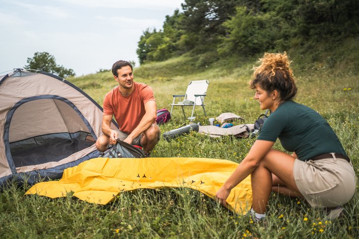 Pareja montando su colchón hinchable camping junto a la tienda